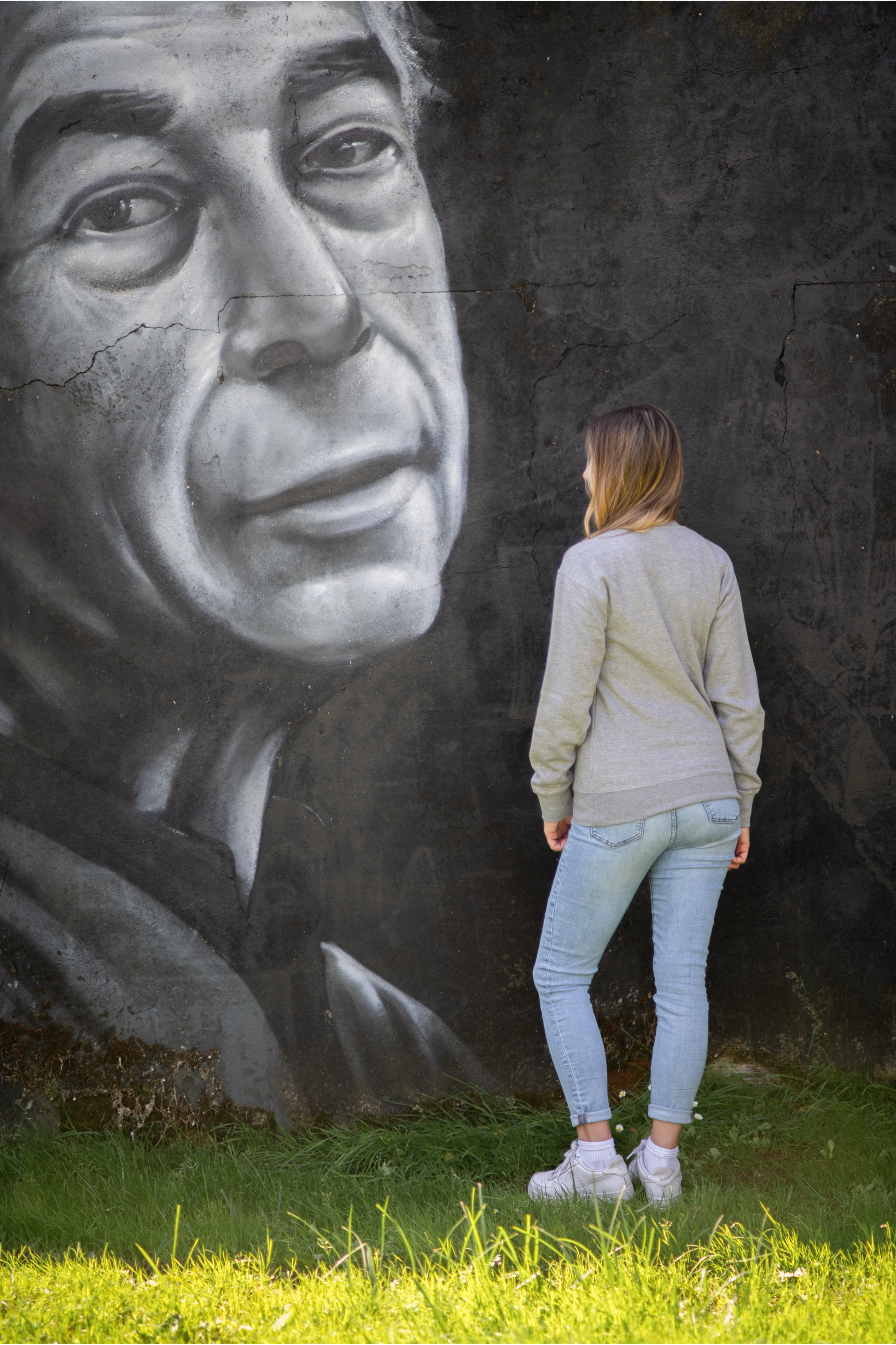 Back view of woman in grey WTF sweatshirt facing large street art mural