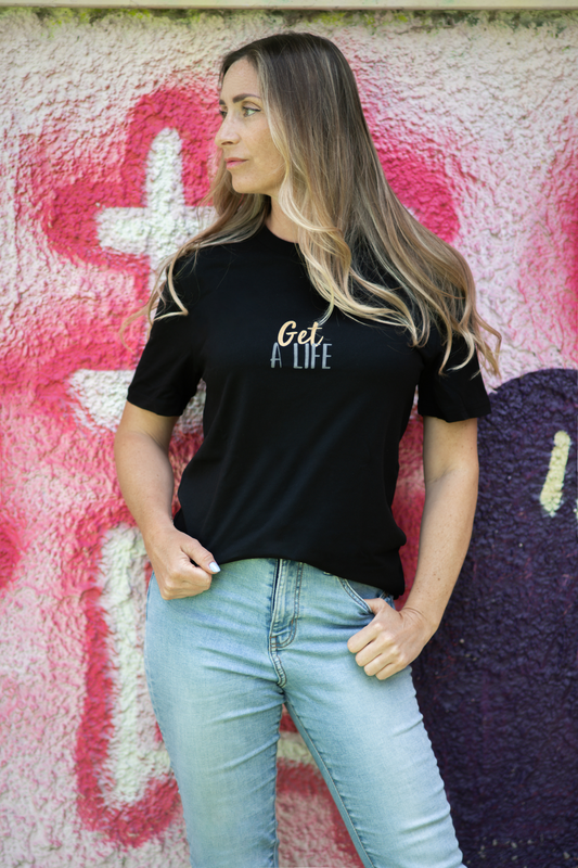 Woman in black Get A Life unisex tee, side view against textured pink and purple graffiti wall